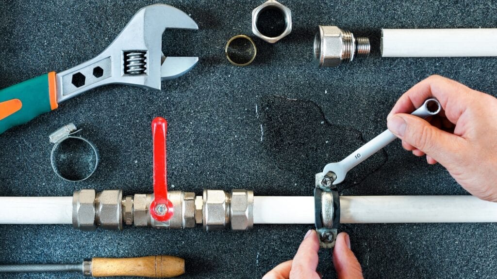 Plumber repairing a pipe valve with an adjustable wrench in Kissimmee