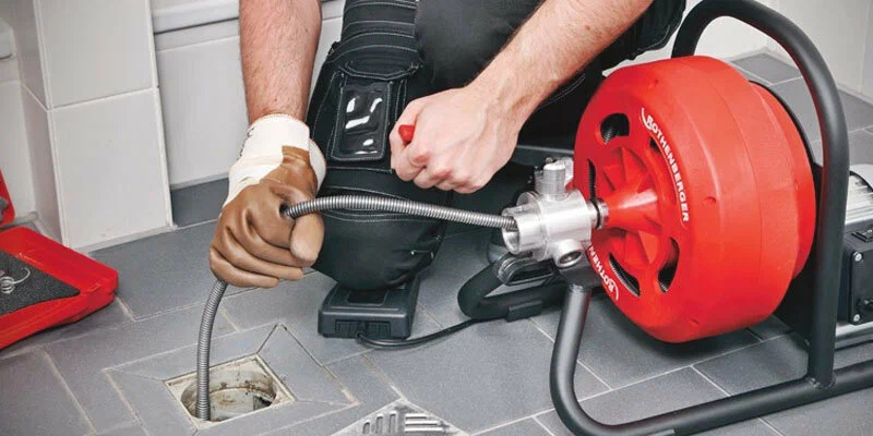 Plumber using a drain-cleaning machine in Kissimmee