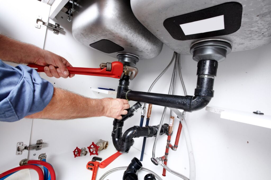 Plumber repairing drain pipes beneath a kitchen sink in Kissimmee