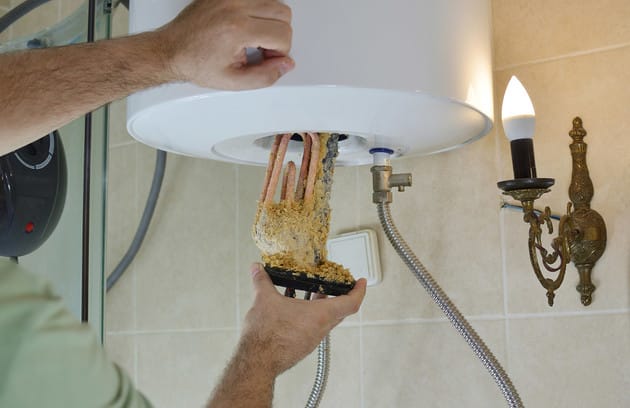 Technician removing mineral buildup from a water heater in Kissimmee